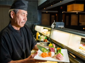 a chef holding a plate of fresh assorted sashimi